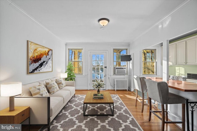 living room with light wood-type flooring, cooling unit, radiator, and crown molding