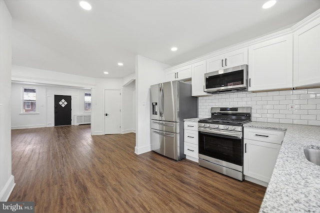 kitchen with radiator, white cabinets, tasteful backsplash, light stone counters, and stainless steel appliances