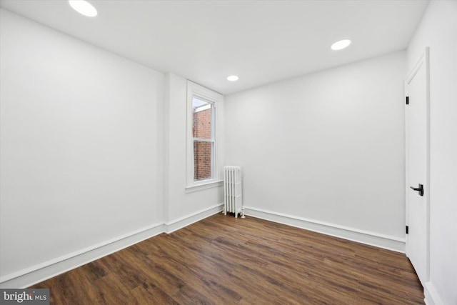 spare room featuring radiator heating unit and dark hardwood / wood-style flooring