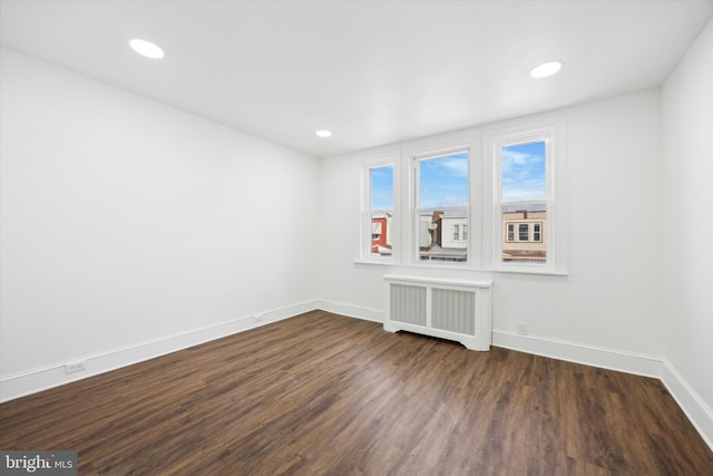 spare room featuring dark wood-type flooring and radiator