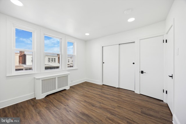 unfurnished bedroom featuring dark hardwood / wood-style flooring, a closet, and radiator