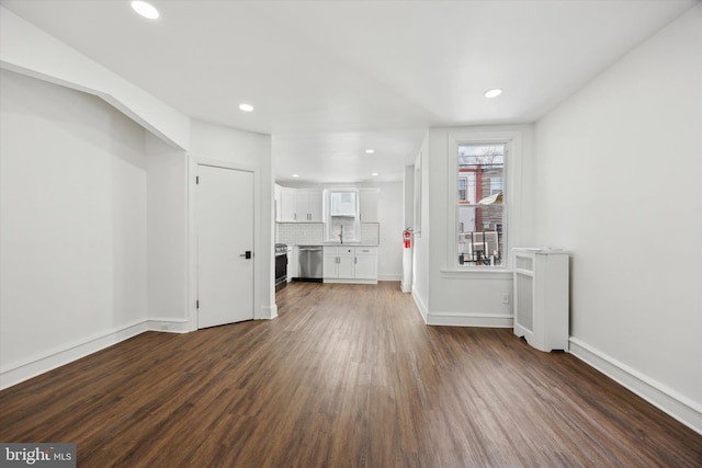 unfurnished living room with dark hardwood / wood-style floors, radiator, and sink