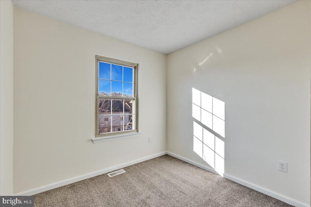 carpeted empty room with a textured ceiling