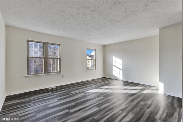 empty room with dark wood-type flooring and a textured ceiling