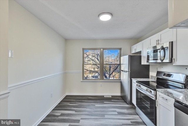 kitchen with dark hardwood / wood-style floors, appliances with stainless steel finishes, a textured ceiling, white cabinets, and light stone counters