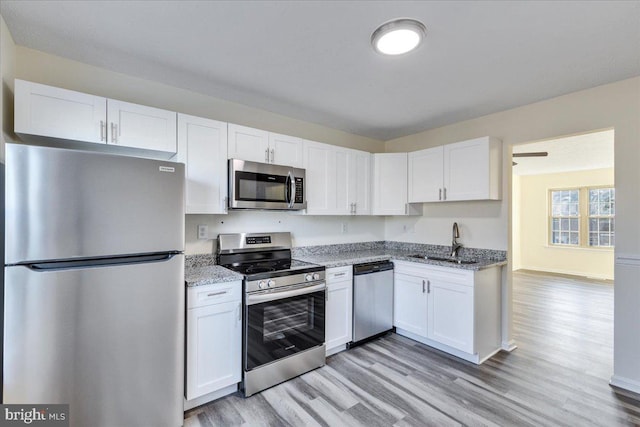 kitchen featuring white cabinets, appliances with stainless steel finishes, sink, and light hardwood / wood-style flooring