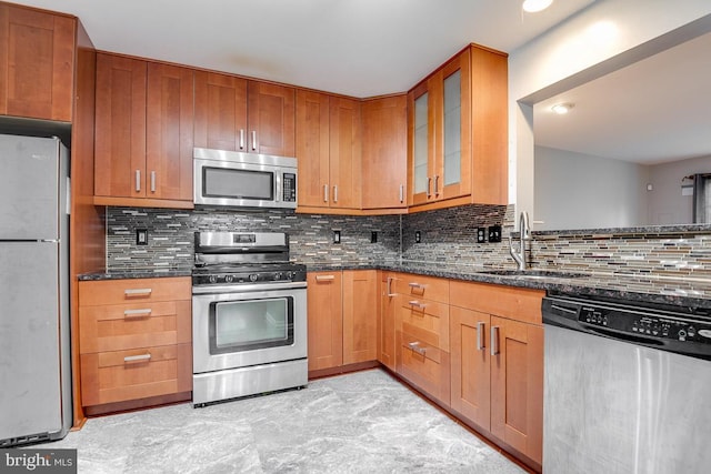 kitchen featuring sink, tasteful backsplash, dark stone counters, and appliances with stainless steel finishes