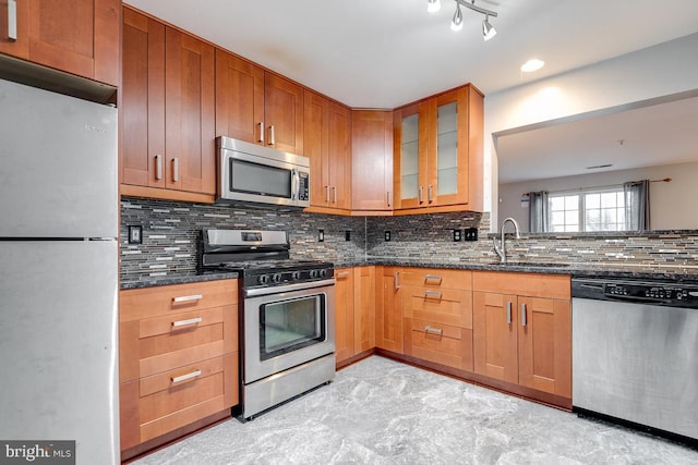 kitchen featuring sink, stainless steel appliances, dark stone countertops, and decorative backsplash