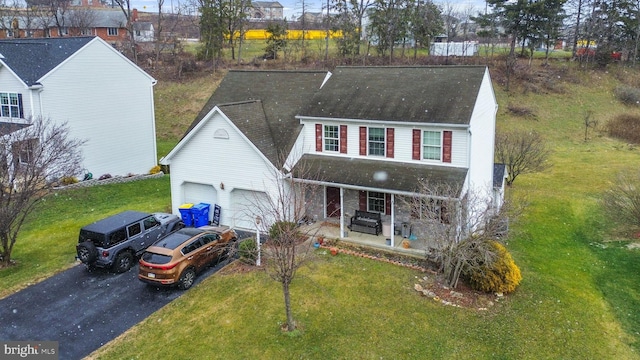 view of front of home featuring a front lawn, covered porch, and a garage