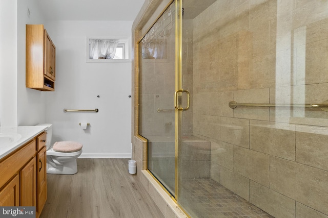 bathroom with toilet, a shower with shower door, hardwood / wood-style flooring, and vanity