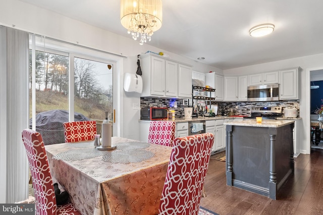 kitchen with decorative light fixtures, appliances with stainless steel finishes, white cabinetry, and a kitchen island