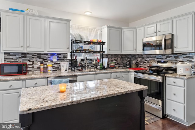 kitchen with appliances with stainless steel finishes, decorative backsplash, a center island, and light stone countertops