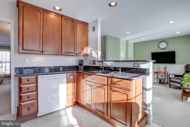 kitchen with sink, dishwasher, kitchen peninsula, and dark stone counters