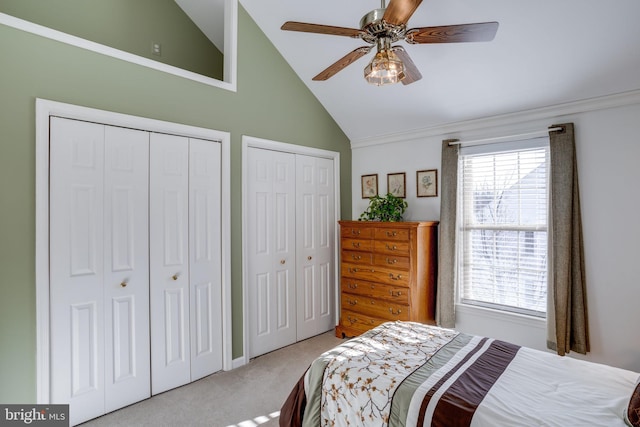 carpeted bedroom featuring ceiling fan, multiple closets, and high vaulted ceiling