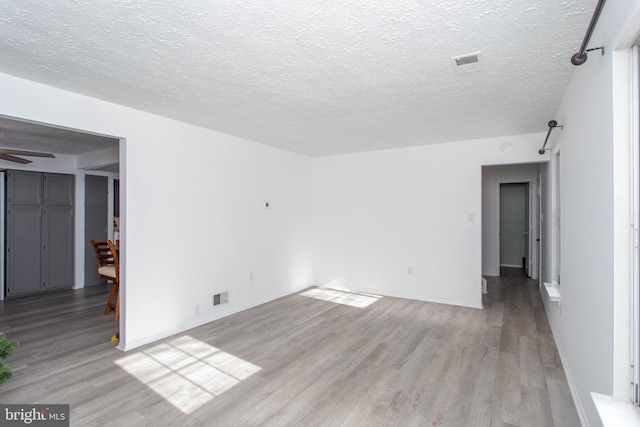 unfurnished room featuring ceiling fan, light hardwood / wood-style floors, and a textured ceiling