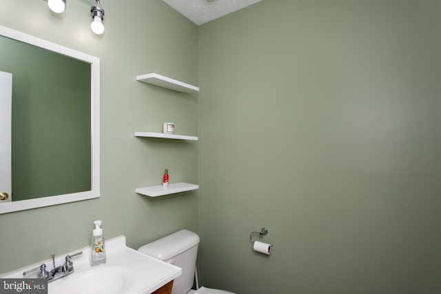 bathroom with vanity, toilet, and a textured ceiling