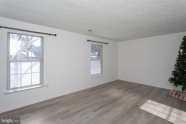 unfurnished room with hardwood / wood-style floors and a textured ceiling