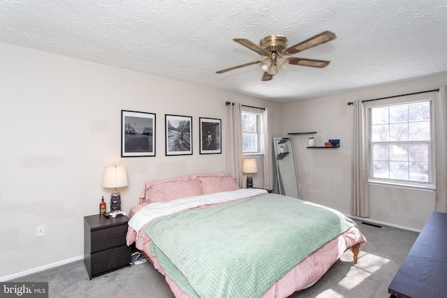 carpeted bedroom with ceiling fan, a textured ceiling, and multiple windows