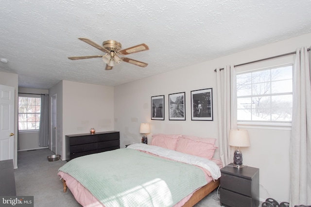 bedroom featuring a textured ceiling, ceiling fan, and light carpet