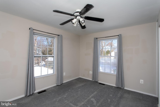 empty room featuring ceiling fan and dark carpet