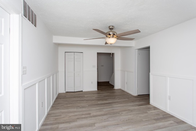 unfurnished bedroom with ceiling fan, light hardwood / wood-style floors, and a textured ceiling