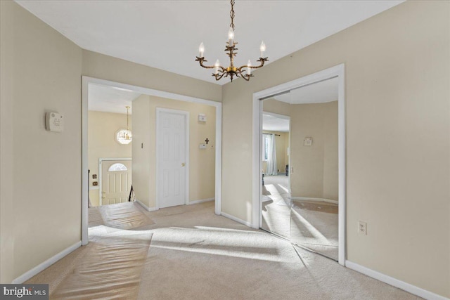 carpeted foyer with an inviting chandelier