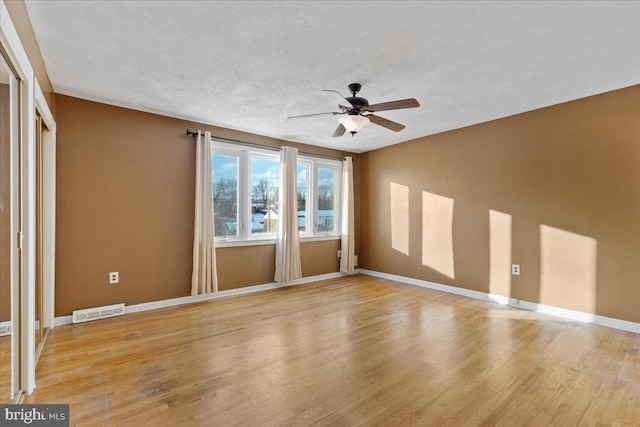 spare room featuring a textured ceiling, light hardwood / wood-style flooring, and ceiling fan