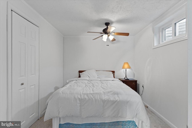 carpeted bedroom with a textured ceiling, a closet, and ceiling fan