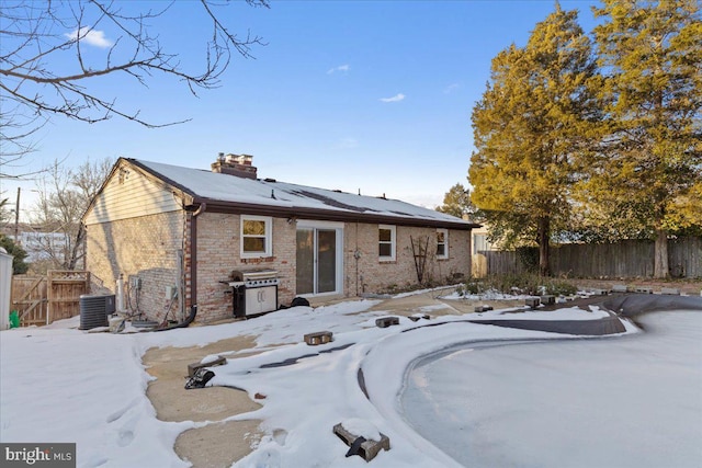 snow covered rear of property featuring cooling unit