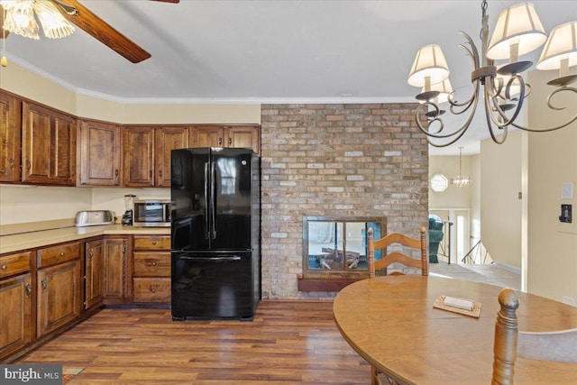 kitchen with black fridge, crown molding, wood-type flooring, decorative light fixtures, and ceiling fan with notable chandelier