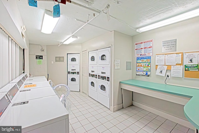 laundry room featuring a textured ceiling, light tile patterned floors, stacked washer and clothes dryer, and washing machine and clothes dryer