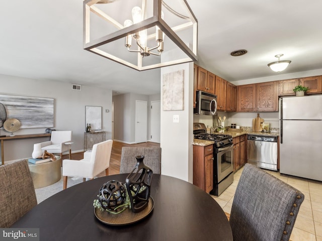 kitchen with hanging light fixtures, appliances with stainless steel finishes, a notable chandelier, and light tile patterned flooring