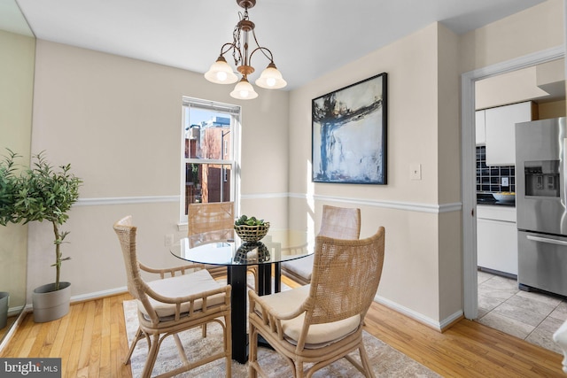 dining space with light hardwood / wood-style floors and an inviting chandelier