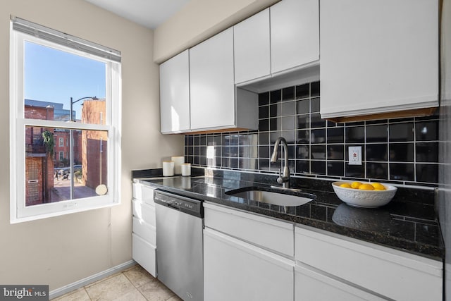 kitchen featuring dishwasher, sink, white cabinets, tasteful backsplash, and dark stone counters