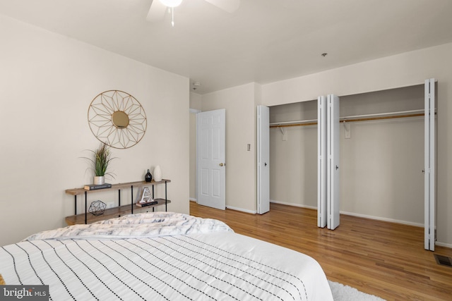 bedroom with wood-type flooring, two closets, and ceiling fan