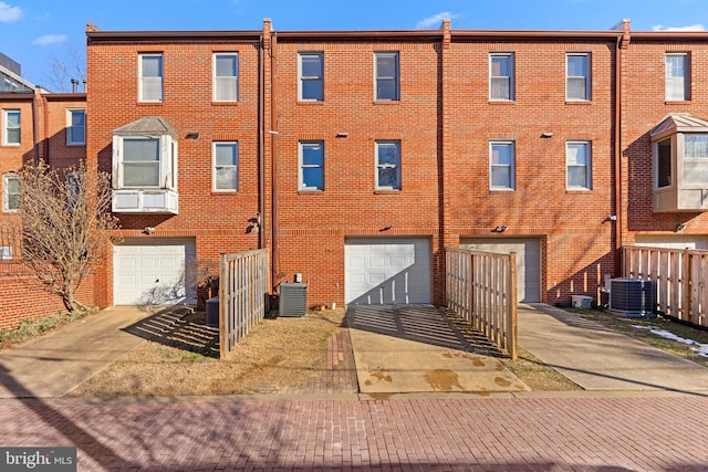 rear view of property featuring central AC unit and a garage