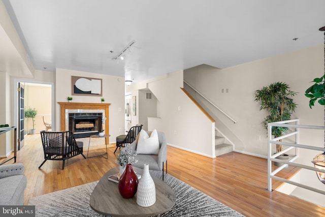 living room featuring rail lighting, light hardwood / wood-style flooring, and a fireplace