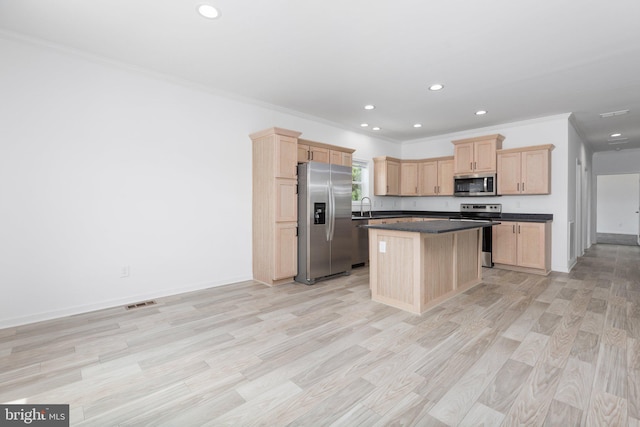 kitchen with light brown cabinetry, appliances with stainless steel finishes, a center island, and ornamental molding