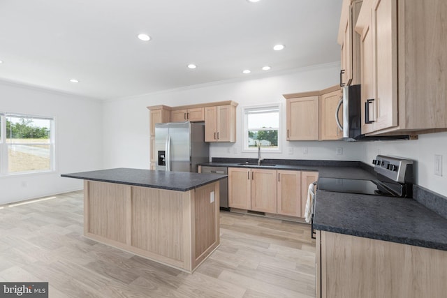 kitchen featuring light brown cabinetry, sink, a center island, and appliances with stainless steel finishes