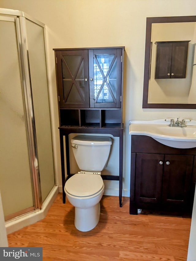 bathroom featuring a shower with shower door, hardwood / wood-style floors, toilet, and vanity