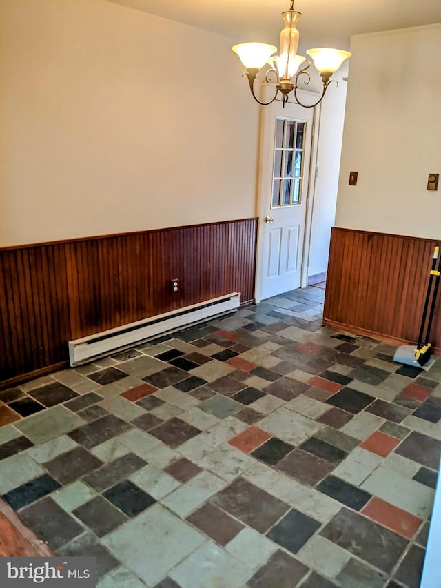 unfurnished dining area with a baseboard heating unit, wood walls, and a chandelier