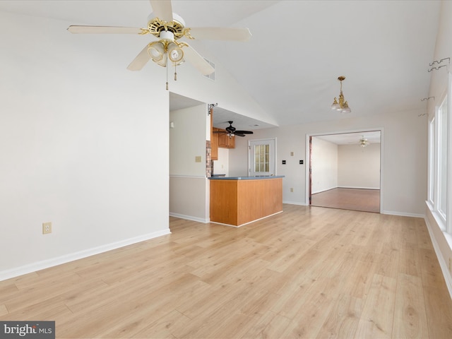 unfurnished living room with high vaulted ceiling, ceiling fan with notable chandelier, and light wood-type flooring