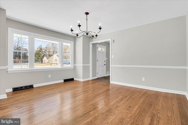 unfurnished dining area featuring hardwood / wood-style floors and an inviting chandelier