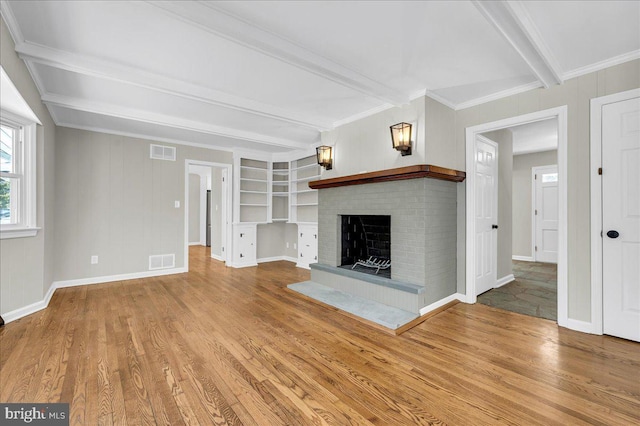 unfurnished living room with beam ceiling, wood-type flooring, ornamental molding, and a brick fireplace