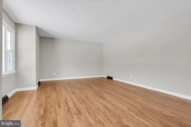 empty room with a wealth of natural light and light hardwood / wood-style flooring