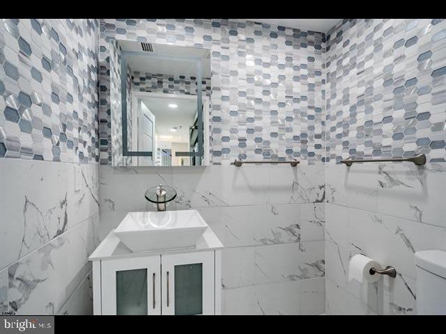 bathroom with vanity, tile walls, and toilet