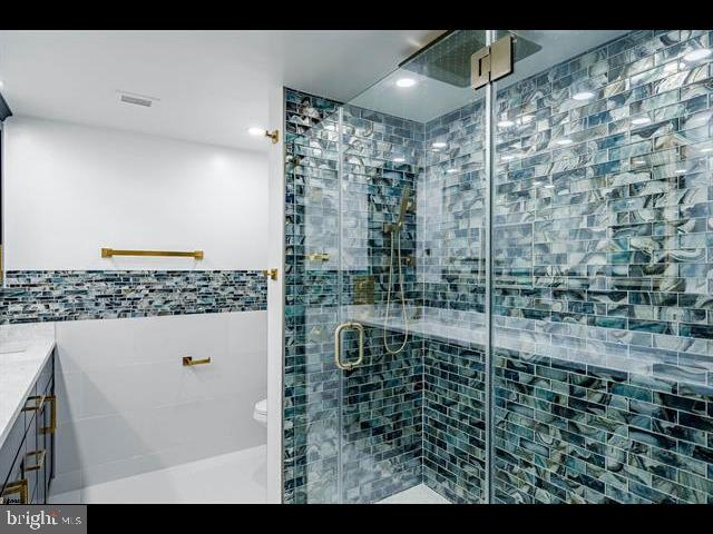 bathroom featuring vanity, toilet, and a shower with shower door