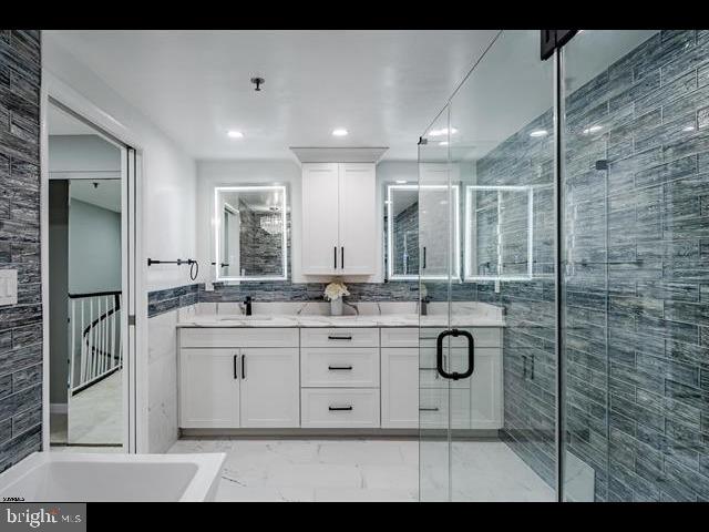 bathroom featuring a shower with door and vanity