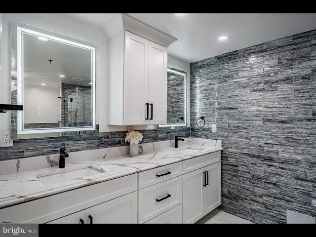 bathroom with tile walls, vanity, and a shower with shower door