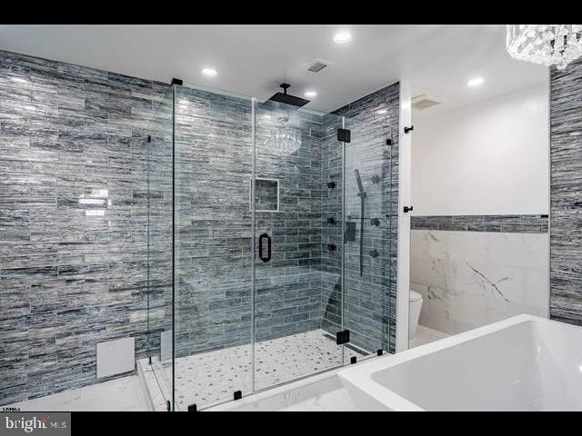 bathroom featuring separate shower and tub, tile walls, and toilet